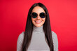 Photo of young pretty charming smiling good mood girl in sunglasses wear striped turtleneck isolated on red color background
