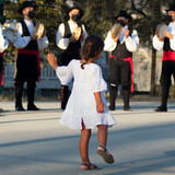 Fototapeta Niebo - child dancing to a traditional group of musicians