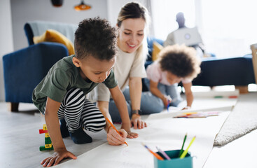 Multi ethnic family with two small children drawing pictures, home office.