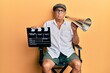 Handsome mature director man holding video film clapboard and louder relaxed with serious expression on face. simple and natural looking at the camera.
