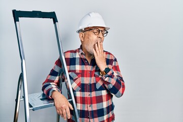 Sticker - Handsome mature handyman close to construction stairs wearing hardhat bored yawning tired covering mouth with hand. restless and sleepiness.