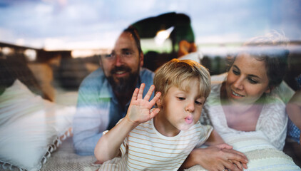 Wall Mural - small boy with parents by window, holiday in nature concept. shot through glass.