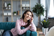 © BestForYou - Beautiful positive woman on the couch talking with friends on a smartphone at home.