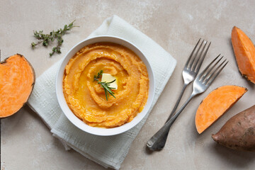 Mashed sweet potato, batata potatoes puree in bowl with butter and herbs.