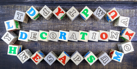 Fototapete - Word - Decoration - in colorful alphabet letters on wooden cubes surrounded by a frame of additional random blocks over a textured textile background. Flat lay, top view