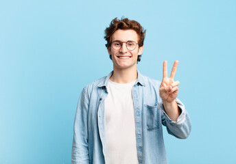 young handsome boy smiling and looking friendly, showing number two or second with hand forward, counting down