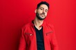 © Krakenimages.com - Young hispanic man wearing red leather jacket looking at the camera blowing a kiss on air being lovely and sexy. love expression.