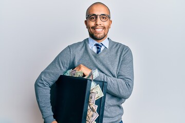 Sticker - Hispanic adult man holding briefcase full of dollars smiling with a happy and cool smile on face. showing teeth.