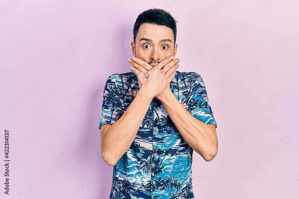 Young hispanic man wearing casual clothes shocked covering mouth with hands for mistake. secret concept.