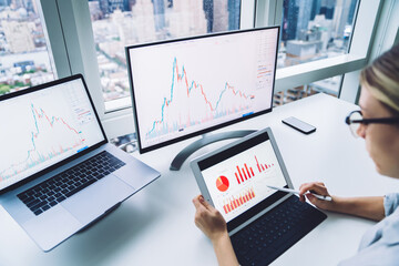 Fototapete - Crop trader analyzing statistics on tablet near computers at work