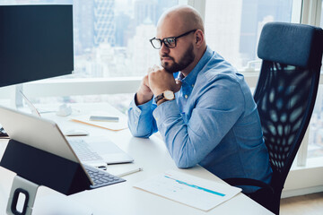 Serious young man analyzing data during work in office