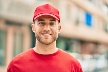 Wall Mural - Young caucasian deliveryman smiling happy standing at the city.