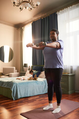 Wall Mural - Full length portrait of African-American woman working out with dumbbells with little girl in background