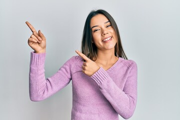 Wall Mural - Young hispanic girl wearing casual clothes smiling and looking at the camera pointing with two hands and fingers to the side.