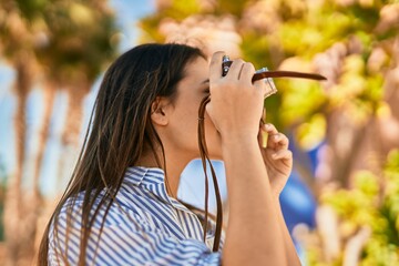 Young hispanic tourist girl smiling happy using camera at the park.