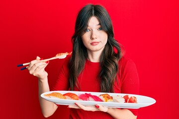 Sticker - Young beautiful caucasian girl eating sushi using chopsticks skeptic and nervous, frowning upset because of problem. negative person.