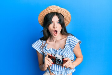 Sticker - Young beautiful caucasian girl holding vintage camera afraid and shocked with surprise and amazed expression, fear and excited face.