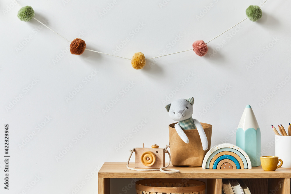 Stylish scandinavian newborn baby room with toys, plush animal, photo camera and child accessories. Cozy decoration and hanging cotton balls on the white wall. Copy space. - obrazy, fototapety, plakaty 