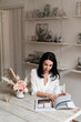 © Natalia - brunette girl in a white shirt reads a magazine at the table