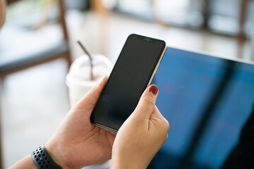 Women hand use smartphone with laptop background on table