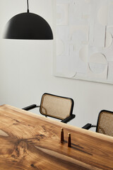 Interior design of stylish dining room interior with family wooden table, modern chairs, plate with nuts,  salt and pepper shakers. Concrete floor. White wall. Template.