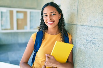 Poster - Young african american student smiling happy and holding book at university.