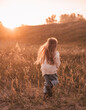 Little girl with long blond hair running in the countryside