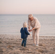 Grandmother plays with her little granddaughter and smiles on the beach
