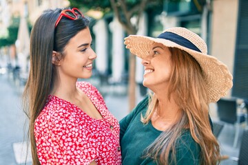 Canvas Print - Beautiful hispanic mother and daughter on vacation smiling happy standing at the city.