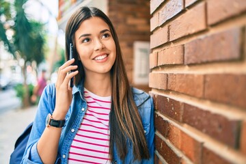 Poster - Young hispanic student girl smiling happy talking on the smartphone at the city.