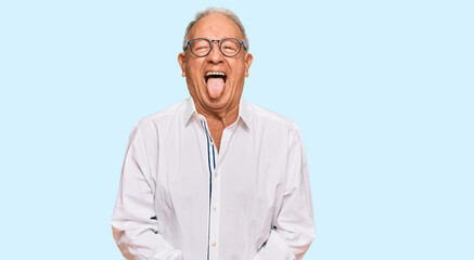 Wall Mural - Senior caucasian man wearing business shirt and glasses sticking tongue out happy with funny expression. emotion concept.