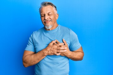 Canvas Print - Middle age grey-haired man wearing casual clothes smiling with hands on chest with closed eyes and grateful gesture on face. health concept.