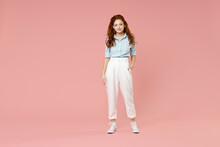 Full Length Body Of Young Student Positive Smiling Happy Caucasian European Redhead Woman 20s Wearing Blue Shirt Pants Standing Looking Camera Isolated On Pastel Pink Color Background Studio Portrait.