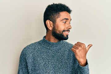 Wall Mural - Handsome hispanic man with beard wearing casual clothes pointing thumb up to the side smiling happy with open mouth