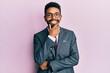 Handsome hispanic business man with beard wearing business suit and tie looking confident at the camera smiling with crossed arms and hand raised on chin. thinking positive.