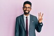 Handsome hispanic business man with beard wearing business suit and tie showing and pointing up with fingers number three while smiling confident and happy.