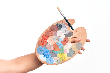 Hand of caucasian young man holding paintbrush and palette with colors over isolated white background