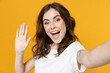 © ViDi Studio - Close up young excited smiling friendly cool caucasian woman 20s in white basic casual tshirt do selfie shot on mobile phone waving hands say hello isolated on yellow color background studio portrait