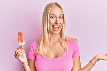 Poster - Young blonde girl holding ice cream celebrating achievement with happy smile and winner expression with raised hand