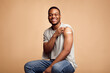© Prostock-studio - Covid-19 Vaccinated African Man Showing Arm With Plaster, Beige Background
