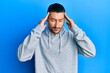 © Krakenimages.com - Handsome man with tattoos wearing casual sweatshirt with hand on head, headache because stress. suffering migraine.