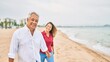 © Krakenimages.com - Middle age hispanic couple smiling happy walking at the beach.
