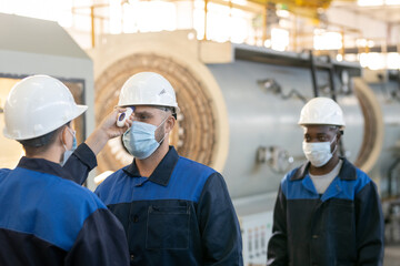 Sticker - One of several factory workers with thermometer measuring body temperature of his colleagues or subordinates inside large workshop