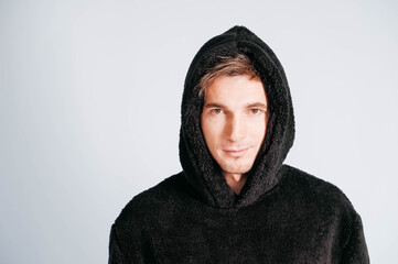 Wall Mural - Portrait of a young man in black sweatshirt with hood on a white background. Copy, empty space for text