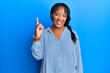 © Krakenimages.com - Middle age african american woman wearing casual clothes smiling with an idea or question pointing finger up with happy face, number one