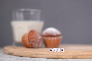 two little cupcakes or muffins in powdered sugar near a glass of milk. healthy breakfast. snack or lunch