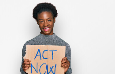 Sticker - Young african american girl holding act now banner looking positive and happy standing and smiling with a confident smile showing teeth