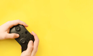 Close-up of a man holding a gamepad and play video games on a yellow background. Place for your text.