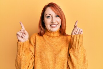 Canvas Print - Beautiful redhead woman wearing casual winter sweater over yellow background smiling confident pointing with fingers to different directions. copy space for advertisement