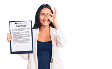 Canvas Print - Young beautiful latin girl holding clipboard with contract document smiling happy doing ok sign with hand on eye looking through fingers